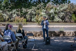 A man speaking to an audience in front of a river.