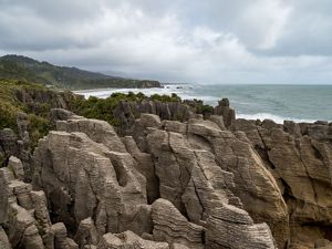 A rocky shoreline made up of thousands of layers of rock in the foreground with the ocean in the background.