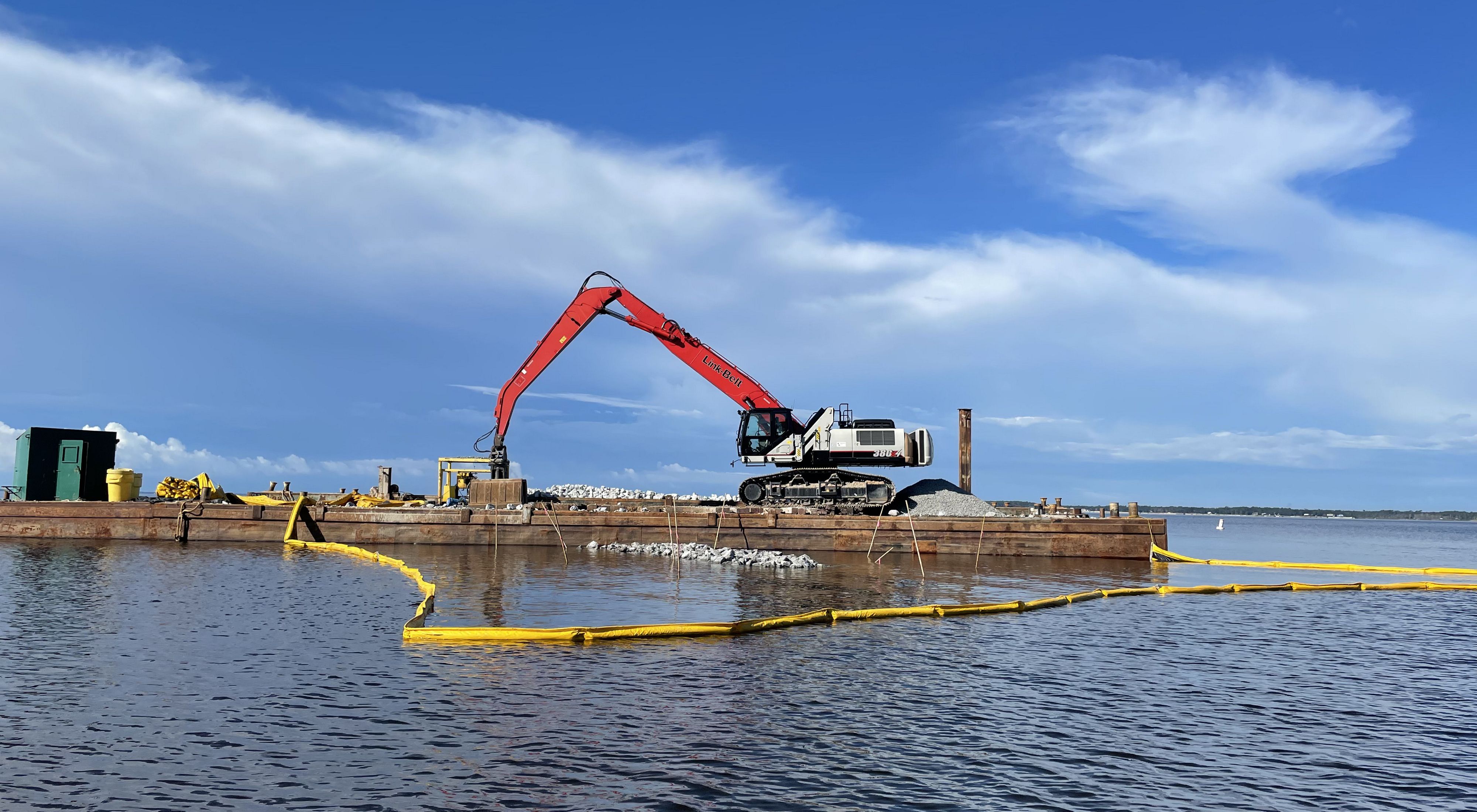An excavator places rocks in the water for oyster reef construction in Florida's East Bay. 
