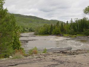 A river runs through dense forest with a forested ridge in the distance.