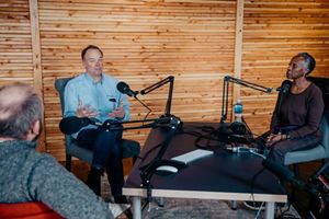 Three people sitting behind microphones talking.