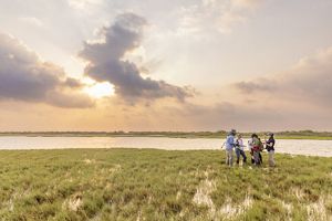 Five people stand together near an expanse of wetlands and water.