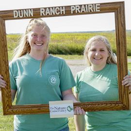 Visitors taking a photo in a wooden frame at the Dunn Ranch Prairie Visitor's Center in Missouri.