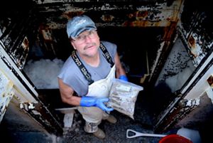 Randy Cushman, a commercial fisherman in the Gulf of Maine, stands in the well of his boat with a bag of frozen fish.