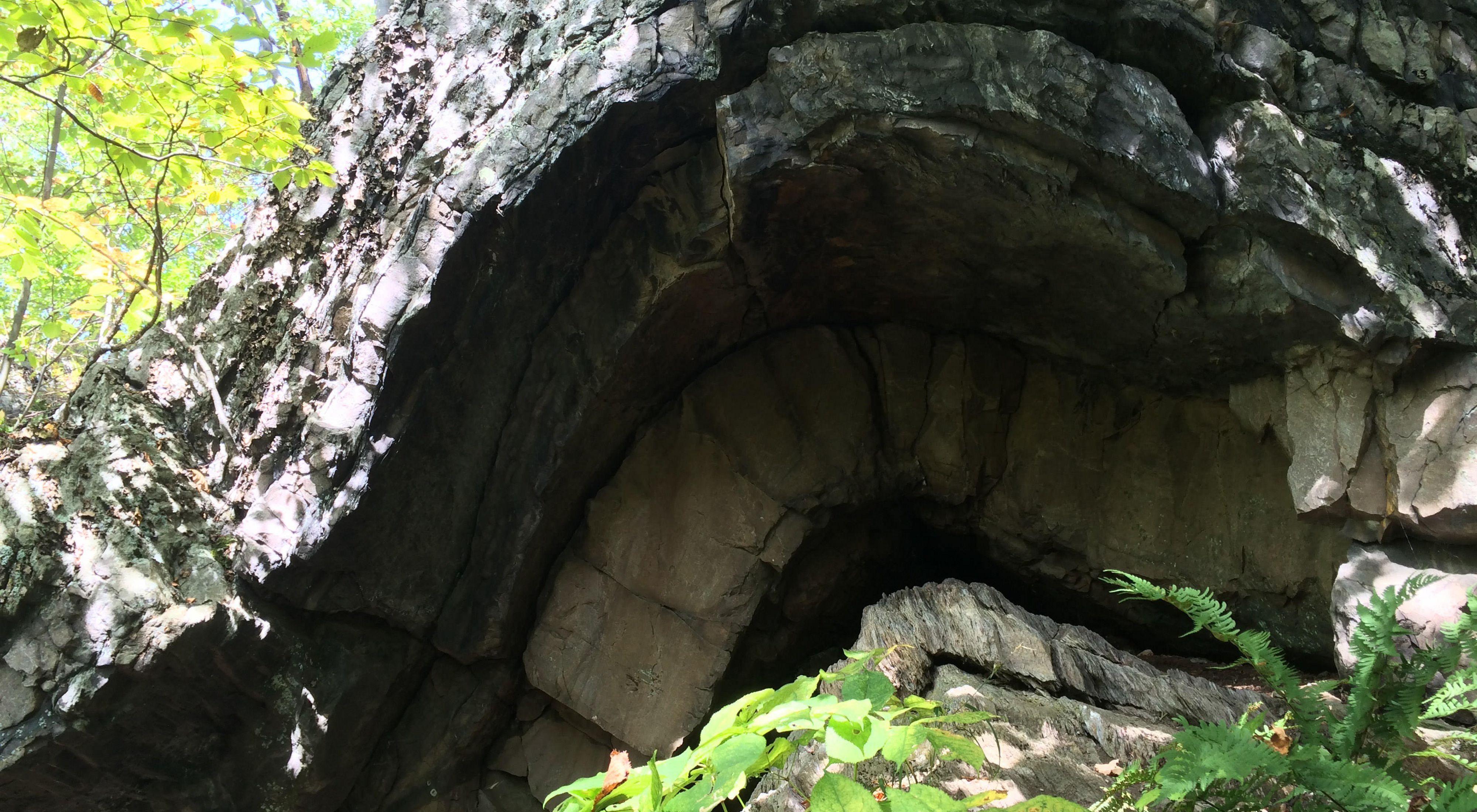 An arched rock formation leading into a cave under the arch.