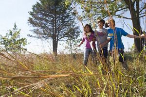 Three children exploring TNC's Nachusa Grasslands Preserve in Illinois under a sunny blue sky.