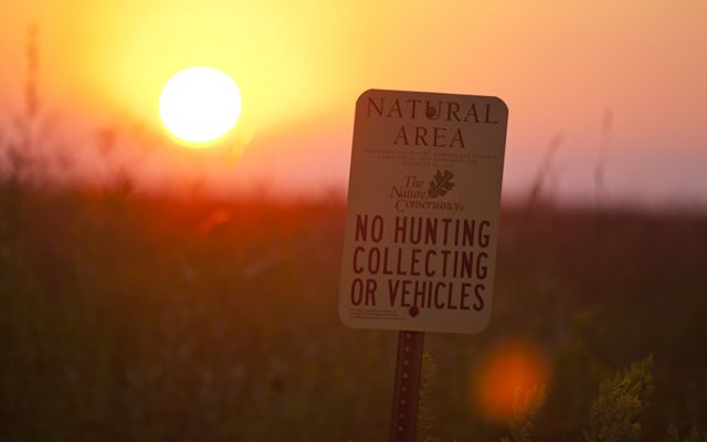 TNC preserve sign against a prairie backdrop at sunrise.