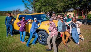 A yellow Rivian truck at Disney Wilderness Preserve is surrounded by TNC staff with smiles.