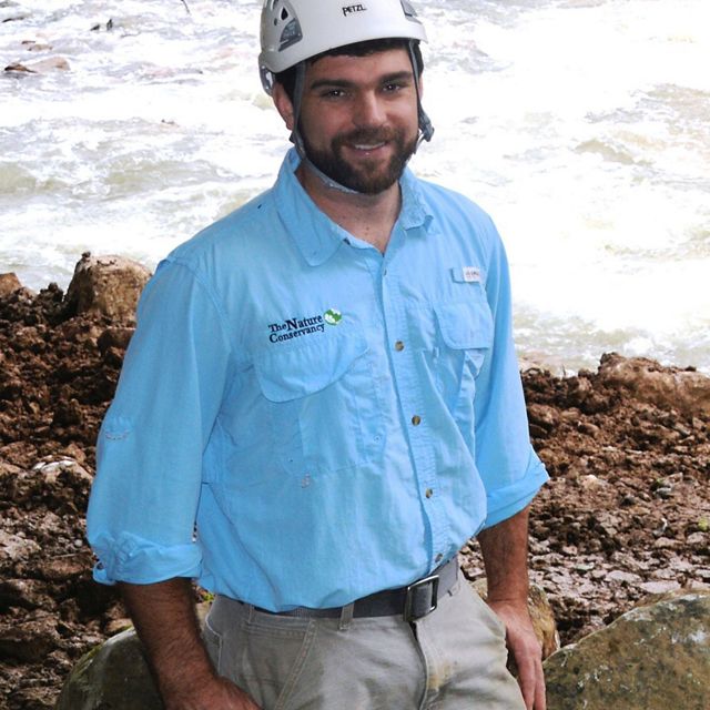 Head shot of a man with a blue Nature Conservancy shirt.