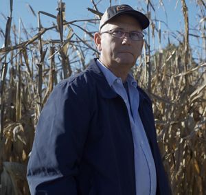 Photo of Robbie Williams standing in front of a corn crop.