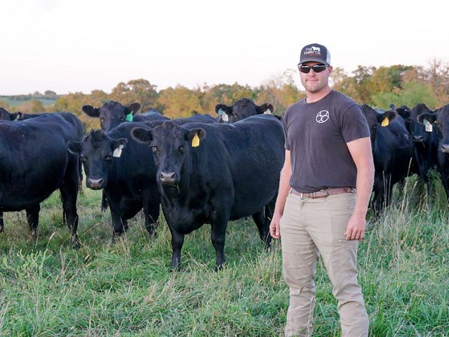 A man standing in front of a herd of cattle.