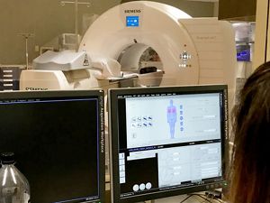 A technician looks at a CT scan graphic on a computer monitor that shows scans of human lungs.