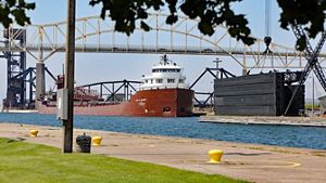 A large ship in a lock close to a bridge, undergoing inspection. 