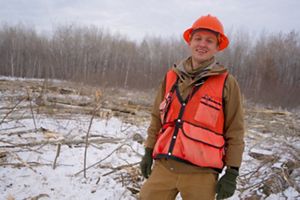 A smiling forester in an orange hard hat.