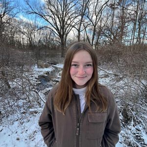 A woman with long brown hair stands in a snowy landscape.