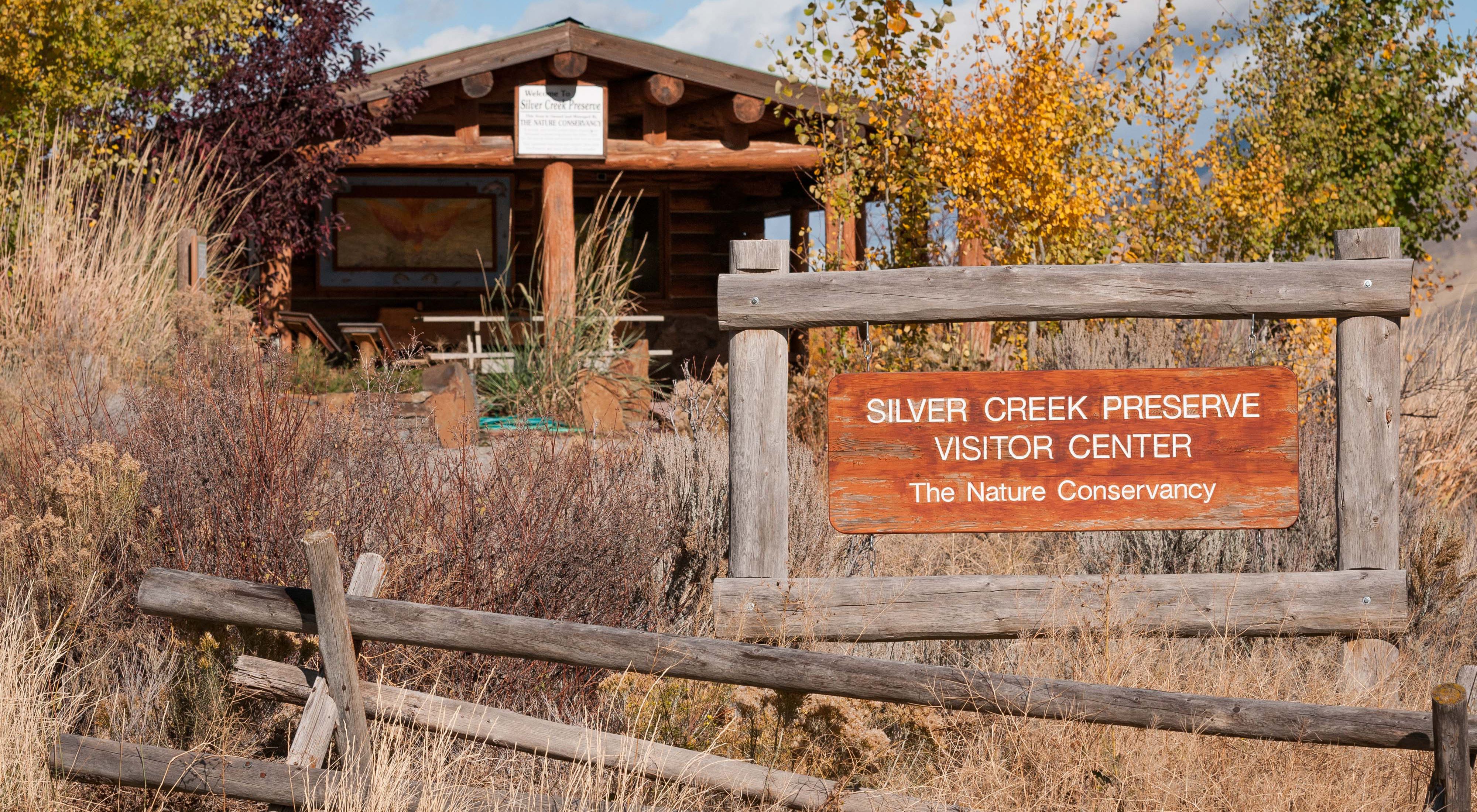 Photo of a welcome sign for visitor center with building in the background.