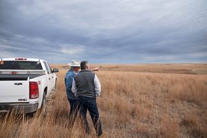 Two men looking out over the rolling hills of a longhorn cattle ranch.