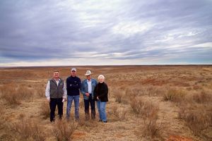 Four people standing in front of a cattle ranch in the Red Hills.