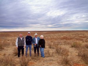 Four people standing in front of a cattle ranch in the Red Hills.
