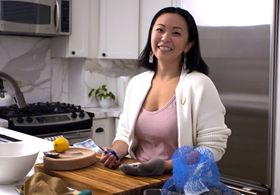 A woman smiling, holding an oyster/shucking knife.