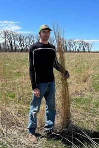 Pete Kronberg holds up blades of grass that reach to his head.