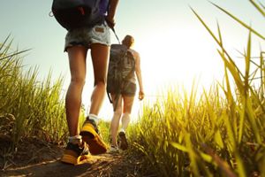 Close-up shot of hikers legs and boots walking in woods.