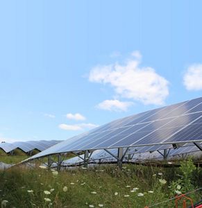Solar panels in a green meadow with blue skies.