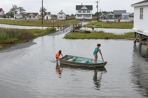 Two girls on a rowboat navigating floodwaters in a neighborhood. 