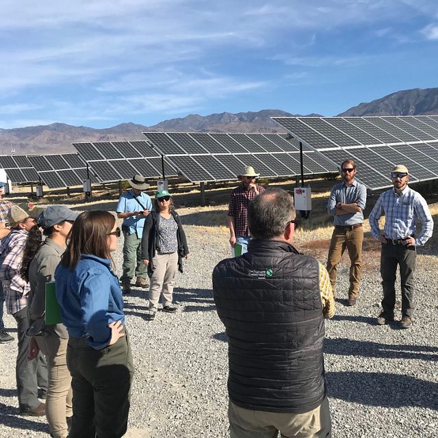 Group of people in discussion beside Nevada solar array