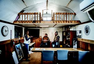 Three people talk within a small room.