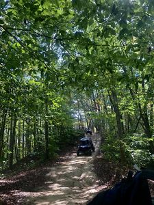 A rider driving down a dirt path, surrounded by tall trees on the Spearhead Trails in Coeburn, Virginia.