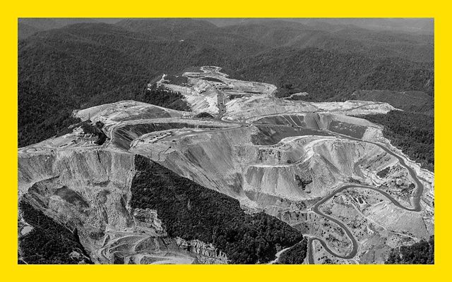 Black and white aerial photo of a mountaintop coal mine in West Virginia, showing degraded land surrounded by forest.