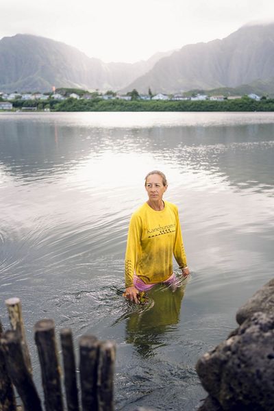 Hi‘ilei Kawelo stands waist deep in the He‘eia fishpond.