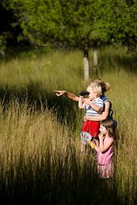 Woman holds child who looks through binoculars.