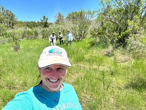 Karen Johnson taking a selfie with three other staff members who are collecting ingredients from a tree.