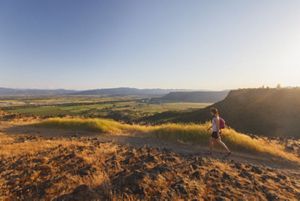 A woman hikes along the edge of Upper Table Rock in OR.
