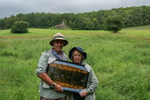 A man and woman hold a framed photo of trees.