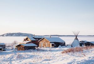 a few small buildings and a teepee covered in snow