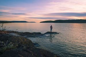 A man stands on an island in Christie Bay, one of the entry points to Thaidene Nene National Park Reserve.