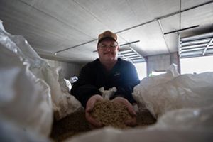 A smiling ag retailer inspects a bag of cover crop seed, ready for planting.