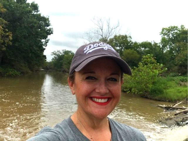 Portrait of a woman wearing a hat standing in front of a river.