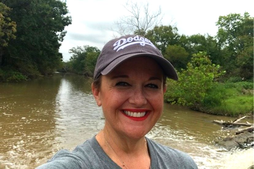 Portrait of a woman wearing a hat standing in front of a river.