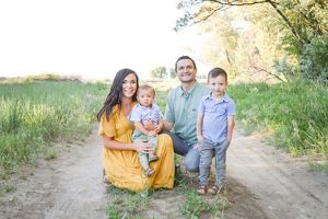 The Wahlen family—two adults and two children—kneel for a family photo on a dirt road.