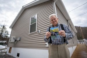 Person holding photo in front of house.