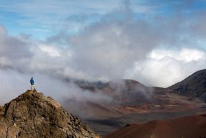 person standing on a mountain looking at a foggy landscape