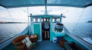 A man stands in the wheelhouse of a crab boat.