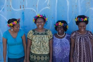 Four Pacific women smiling against a blue background.