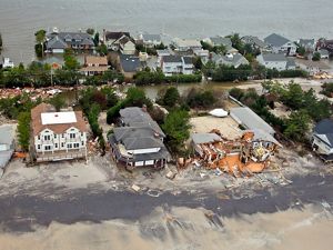 Coastal community post-Sandy with sand-covered, damaged houses.