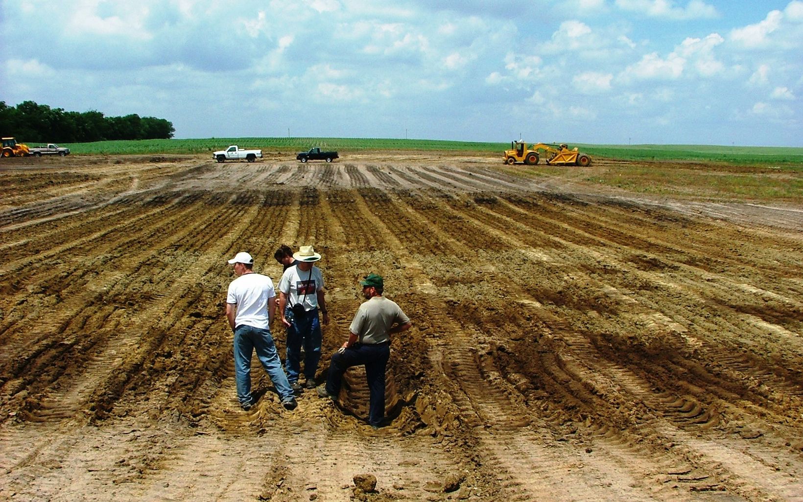 Farmers survey soil in recently plowed field.