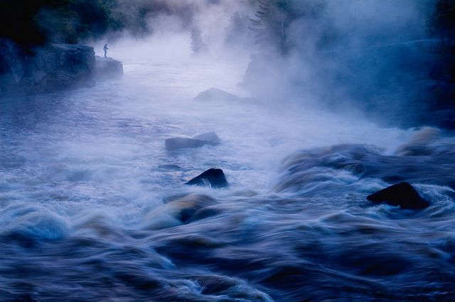 A man casts a fly line in the early morning fog on the East Branch of the Penobscot River in Maine.